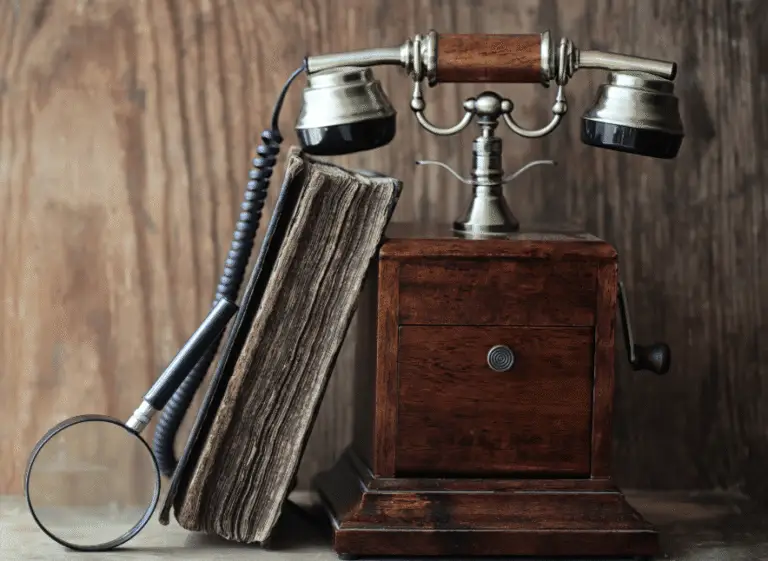 Vintage rotary telephone, magnifying glass, and weathered book on a wooden table—symbolizing personal consultation and trusted support.